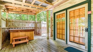 A covered wooden deck with a wooden bench and a hot tub. - Cub's Den: Beautifully Located, Cozy Cabin Surrounded by The Great Smoky Mountains (Gatlinburg)