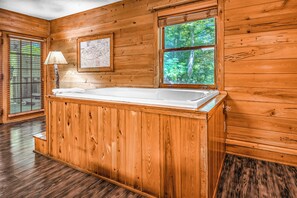Relax in a serene space with a large bathtub, wooden paneling, and a map on the wall.