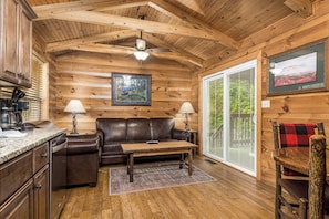 Relax in this cabin-style room with a wooden ceiling, leather sofa, and a view of the surrounding greenery.