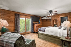 A wooden cabin bedroom with a bed, dresser, TV, and a ceiling fan. - Valentines View: Majestic Lodge with Awe-Inspiring Views (Sevierville)