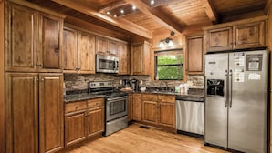 Eine Küche mit Holzmöbeln, einem Edelstahl-Kühlschrank, Backofen und einer Mikrowelle.