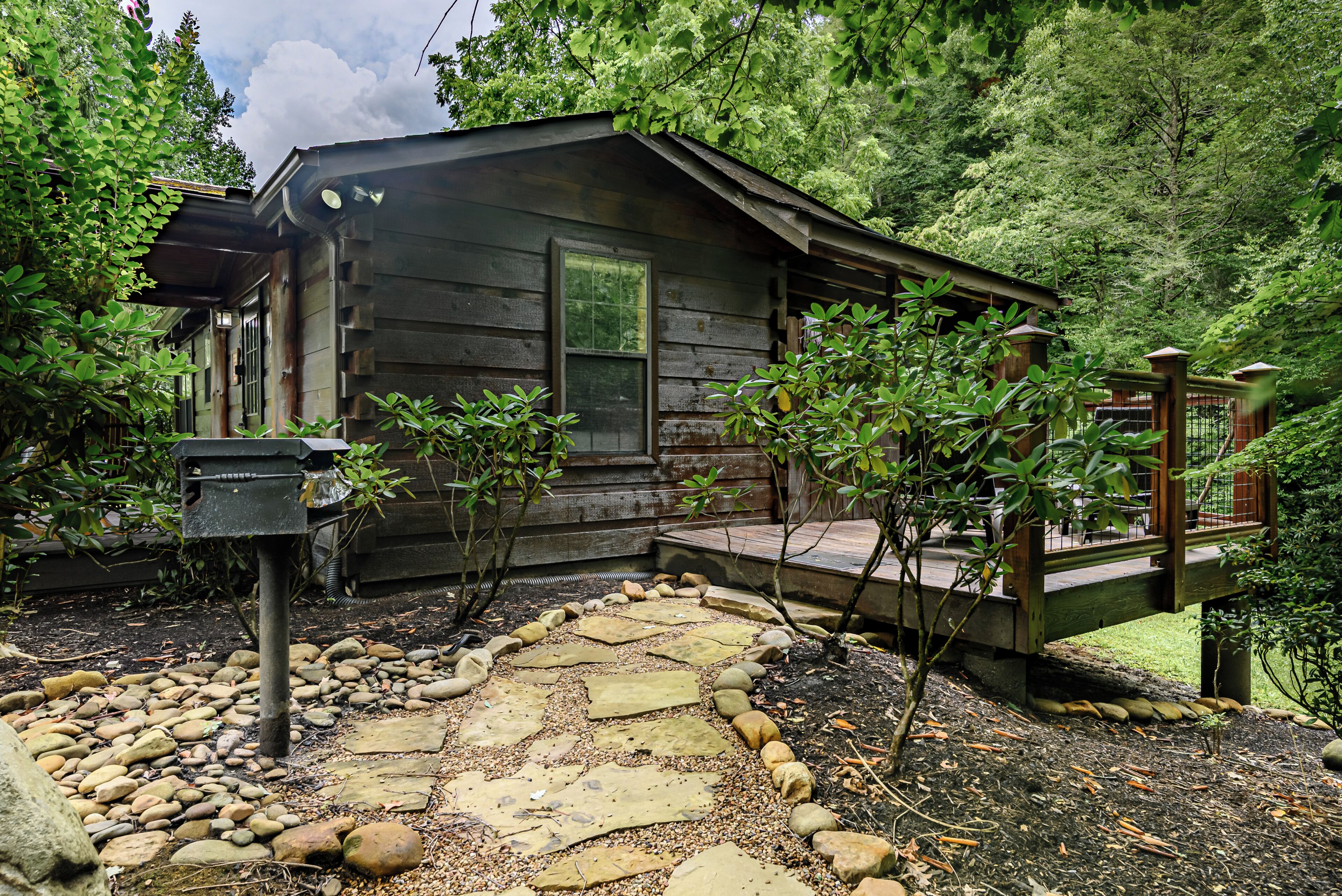 Un chalet rustique avec un sentier de pierres menant à une terrasse en bois.