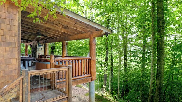Een houten chalet met veranda, een eethoek en uitzicht op een dicht bos.