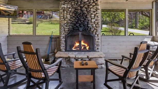 A stone fireplace with a fire, surrounded by outdoor seating. - Smoky Cove: Gorgeous, Pet Friendly Cabin located only 1 mile from Gatlinburg City limits! (Sevierville/ Pittman Center)