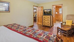 A bedroom with a bed, a quilt, a wooden dresser, a television, and a ceiling fan. - Smoky Cove: Gorgeous, Pet Friendly Cabin located only 1 mile from Gatlinburg City limits! (Sevierville/ Pittman Center)