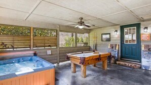 A pool table, a hot tub, and a door with a sign in a covered outdoor area. - Smoky Cove: Gorgeous, Pet Friendly Cabin located only 1 mile from Gatlinburg City limits! (Sevierville/ Pittman Center)
