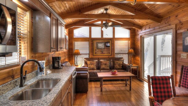 A log cabin interior with a kitchen, dining area, and seating space.