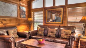 A cozy cabin interior with leather sofas, a wooden coffee table, and a map on the wall.