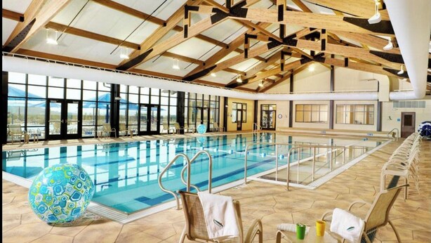 A large indoor swimming pool with a high ceiling and wooden beams, surrounded by large windows and a view of the outdoors. - Charming, Farmhouse Chic, Cozy|Fireplace|12 Min to Town|Beautiful View (Galena)