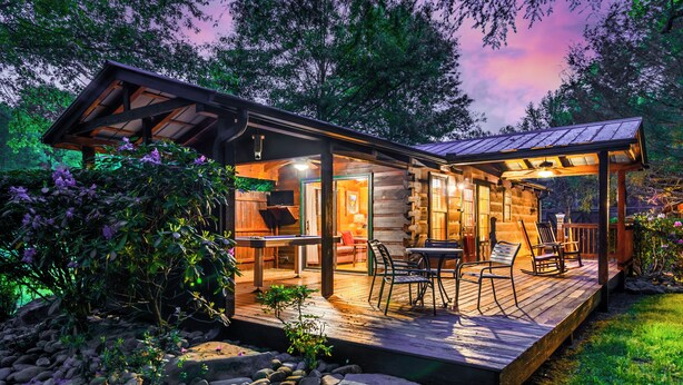 Una cabaña de madera con un balcón, mobiliario exterior y un porche cubierto.