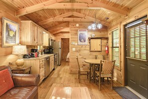 A wooden cabin interior with a kitchen, dining area, and a couch.