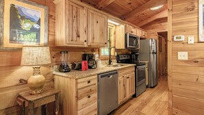 Cocina de cabaña de madera con encimera de granito, electrodomésticos de acero inoxidable y armario de madera.