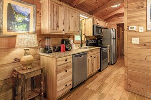 A wooden cabin kitchen with a granite countertop, stainless steel appliances, and a wooden cabinet.
