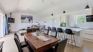 A modern kitchen with white cabinets, a central island, and bar stools.