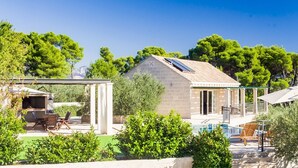 A modern house with a patio, a barbecue area, and a swimming pool.