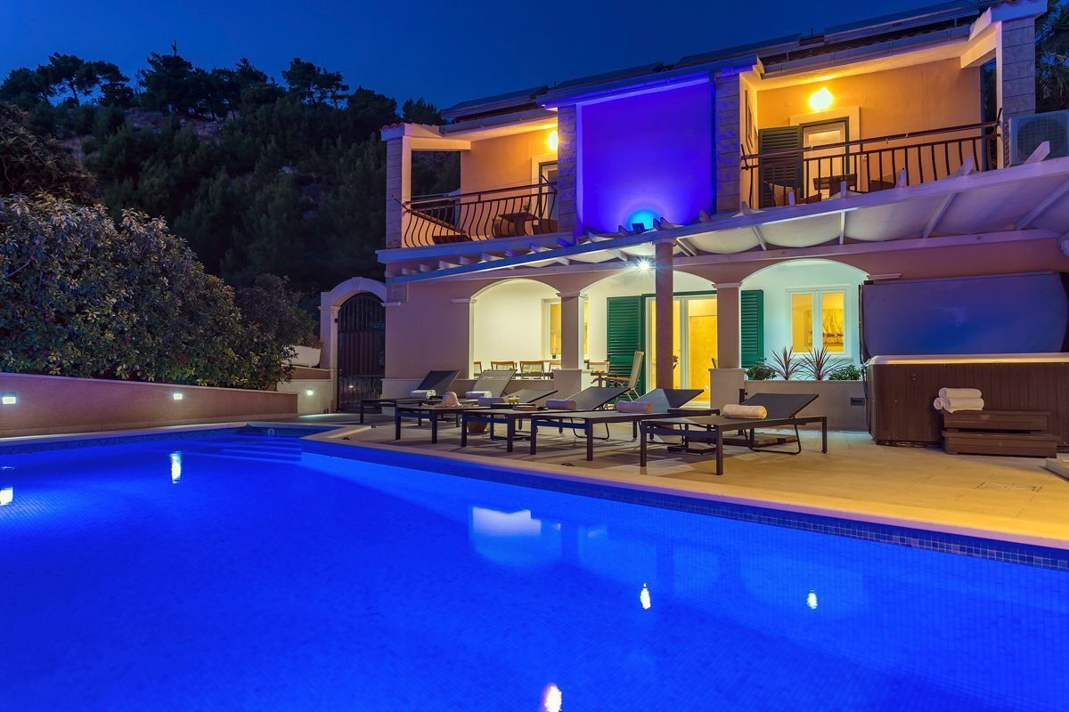 A two-story building with a swimming pool, outdoor seating, and a hot tub.