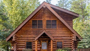 A log cabin with a symmetrical facade, a central entrance, and a small porch.