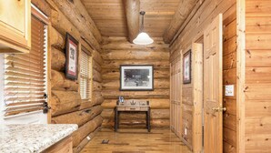 A wooden interior with a wooden table, framed pictures, and a wooden door.
