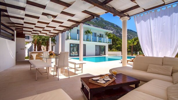 A modern outdoor seating area with a pool, a dining table, and a sofa.