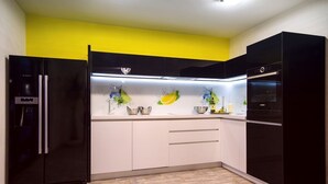 A modern kitchen with black appliances, white cabinets, and a yellow accent wall.