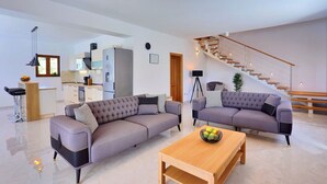 A modern living room with two sofas, a wooden coffee table, and a staircase with wooden railings. - Villa Nedy - Four Bedroom Villa, Sleeps 8 (Zakucac)