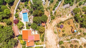 Eine Vogelperspektive auf ein Anwesen mit Schwimmbad, Tennisplatz und einem eingezäunten Bereich mit Spielplatz.