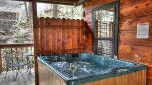 A hot tub with a wooden deck, a glass, and a safety rules sign.