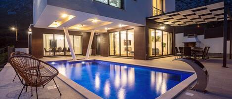 Een verwarmd zwembad, ligstoelen bij het zwembad