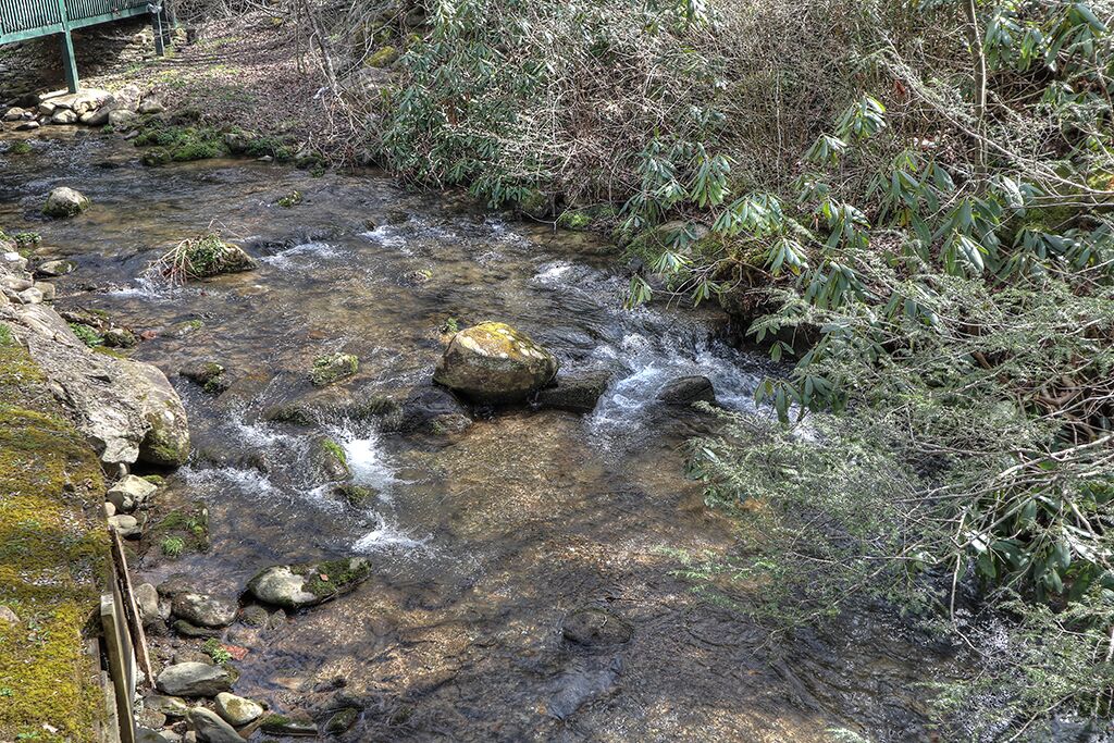 A rocky stream with a wooden bridge in the background.