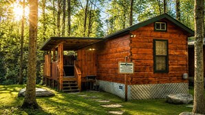 Une cabane avec une façade en bois, une véranda et une pancarte indiquant qu’il s’agit d’une location de vacances.