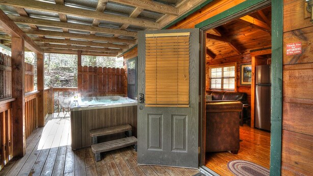 Une cabane dotée d’un bain à remous, d’une terrasse en bois et d’un coin cuisine.