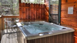 Un bain à remous sur une terrasse en bois, avec une clôture en bois et une fenêtre équipée de stores.