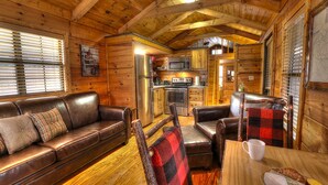 Een gezellig interieur van een chalet met houten details, een leren bank, een eettafel en een keuken.