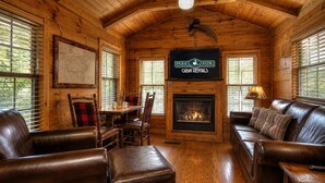 Interieur van een chalet met een open haard, lederen meubels en een bordje voor chaletverhuur.