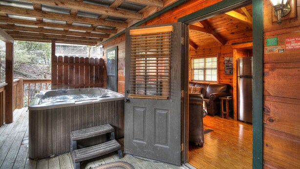 Een houten chalet met een bubbelbad, een eethoek en een keuken.