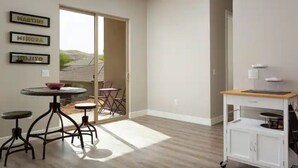 A spacious room with a large sliding glass door leading to a balcony, a small round table with stools, and a white cabinet with drawers. - Amazing VIEWS, NEW quiet home, bonus Fitness Room! (Hurricane)