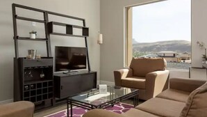 A modern living room with a large window, a flat-screen TV, a sofa, and a coffee table. - Amazing VIEWS, NEW quiet home, bonus Fitness Room! (Hurricane)
