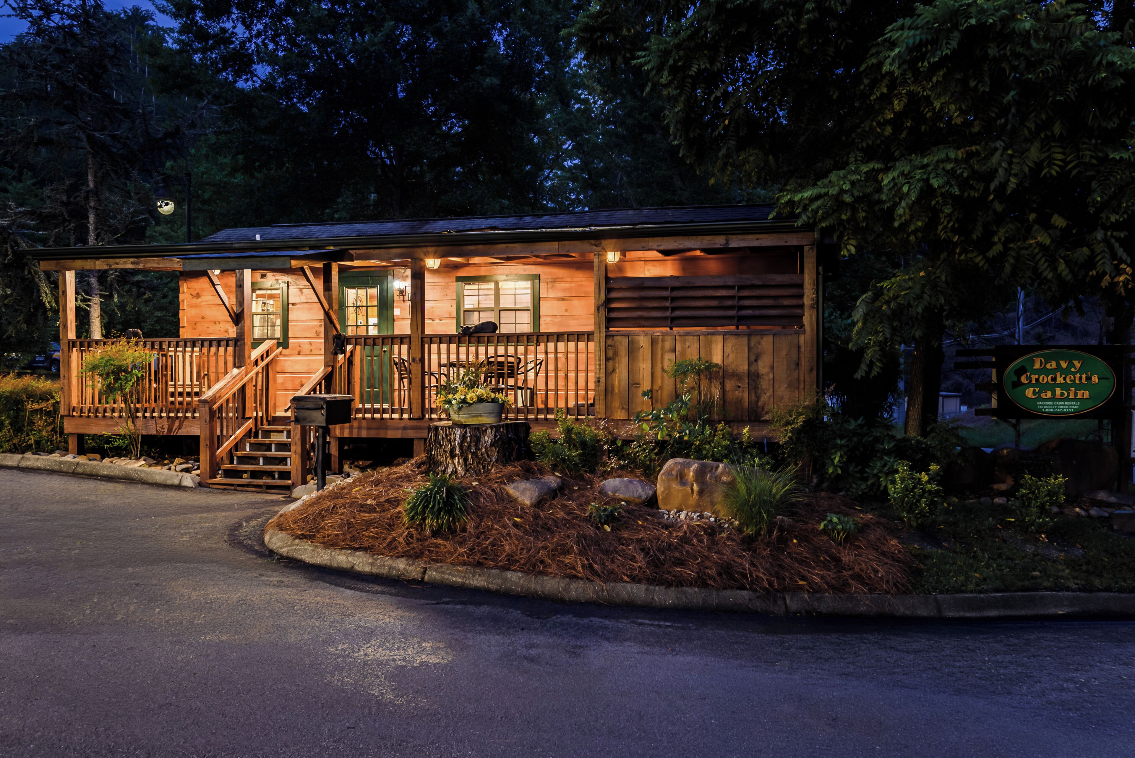 A wooden cabin with a porch, steps, and a sign indicating it is a rental property.