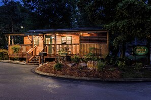 A wooden cabin with a porch, steps, and a sign indicating it is a rental property.