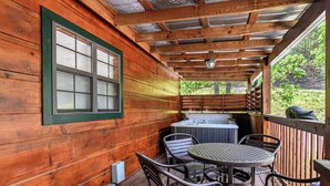 A wooden deck with a hot tub, wicker chairs, and a table.
