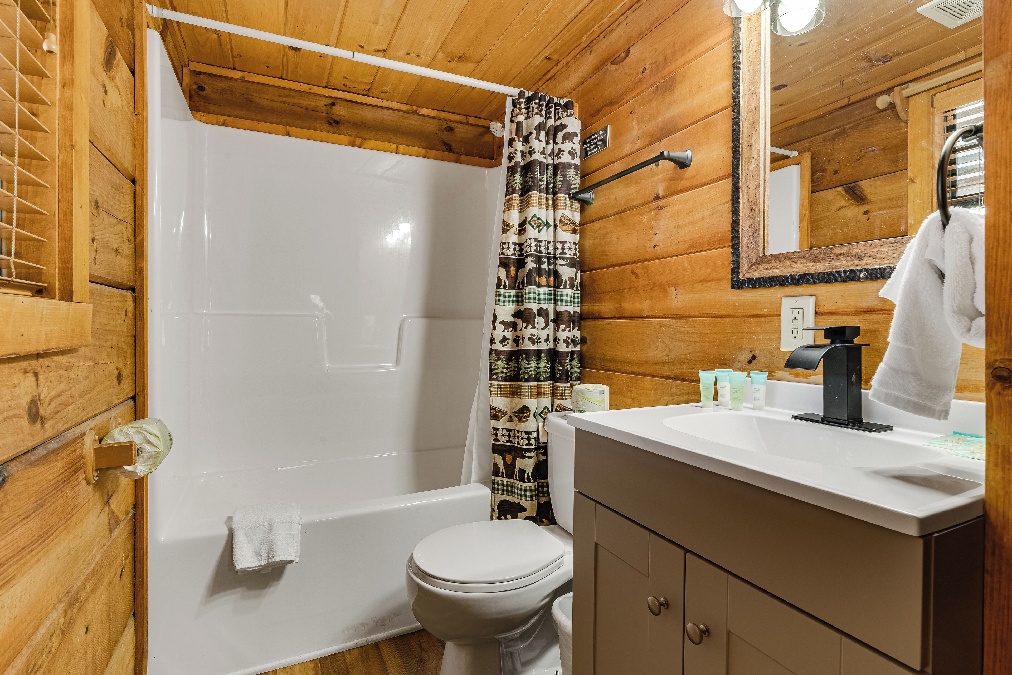 A wooden cabin bathroom with a shower, toilet, and vanity.