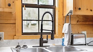 A kitchen with a double sink, a modern faucet, a window with a view, and wooden cabinets.