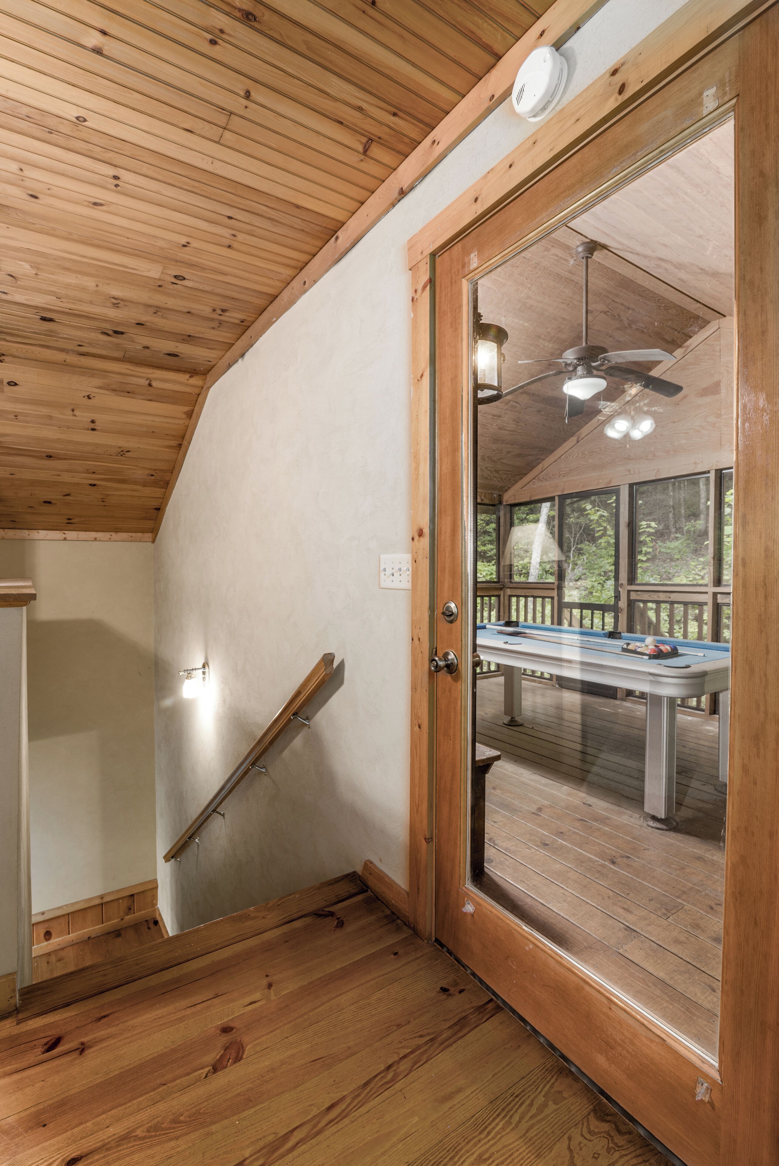 A wooden interior with a glass door leading to an outdoor deck area.