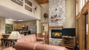 Una sala de estar acogedora con chimenea, televisor y una pared de acento de piedra.