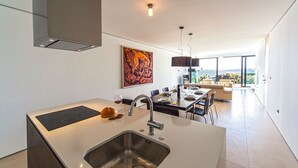 Una cocina moderna con una isla central, un lavamanos de acero inoxidable y una zona de comedor con vistas.