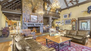 A spacious living room with leather sofas, a fireplace, and a stone wall.