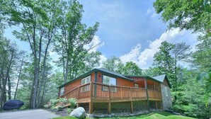 Une cabane en bois dotée d’une terrasse, entourée d’arbres et offrant une vue sur un ciel dégagé.