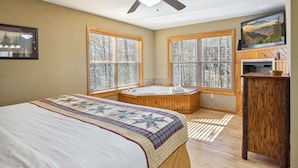 Une chambre à coucher avec un grand lit, une baignoire en bois et un ventilateur de plafond.