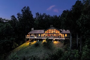 A wooden cabin with a balcony, surrounded by trees.