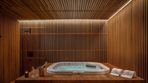 Un espace spa avec un sol en bois, un jacuzzi, des bougies et des serviettes.